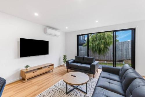 a living room with a couch and a tv at "Elegant Home in Highton near City City" in Geelong