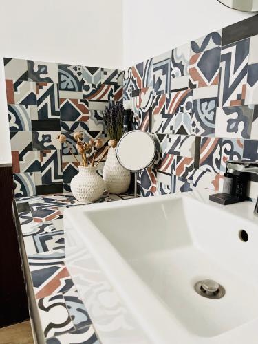 a bathroom with a sink and a patterned wall at Butera Apartments Luxury in Palermo