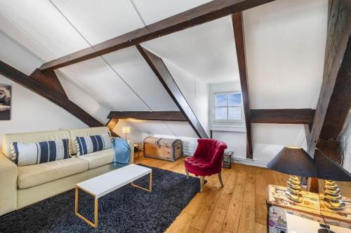 ein Wohnzimmer mit einer Couch und einem roten Sessel in der Unterkunft Marais Rooftop Apartment in Paris