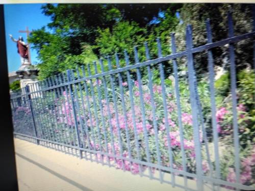 a fence in front of a garden with pink flowers at Entre mer et cevennes in Boisseron