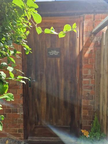 a wooden door in a brick wall at The Nook- Cotswold guest room in Mickleton