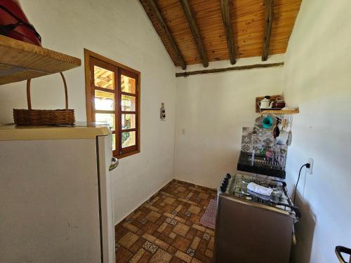 a kitchen with a refrigerator and a window at Chalés Vila Carrancas - Ao lado do centro com piscina, cozinha completa e muita tranquilidade in Carrancas