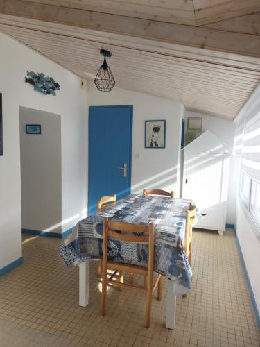 une salle à manger avec une table, des chaises et une porte bleue dans l'établissement Gîte la Salicorne, à Les Sables-dʼOlonne