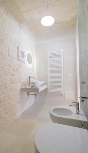 a white bathroom with a tub and a sink at Dimora del Tenente in Locorotondo