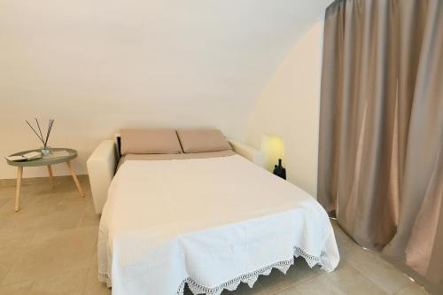 a bedroom with a white bed and a table at La Scala del Borgo in Cisternino