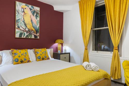 a bedroom with a bed with yellow curtains and a window at Hyde Park Arty Apartment in London