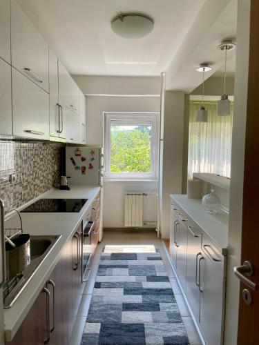 a kitchen with white cabinets and a window and a rug at Maria Charming Apartment in Kumanovo