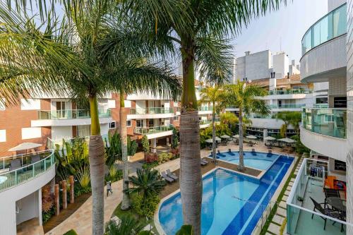 an aerial view of a hotel with a pool and palm trees at Boulevard Bombinhas - Apto em Condomínio com Piscina e Jacuzzi in Bombinhas