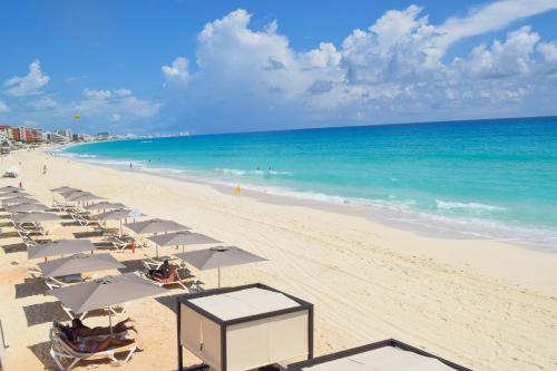 a beach with chairs and umbrellas and the ocean at New studio at the Beach, pool, gym, spa 2D in Cancún