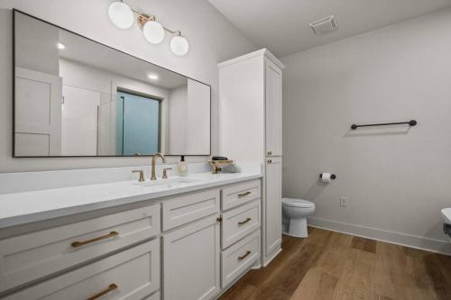 ein weißes Badezimmer mit Waschbecken und Spiegel in der Unterkunft Lake Ouachita's Luxury Lake House in Mount Ida