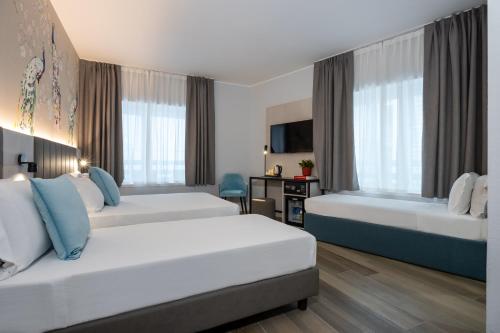 a hotel room with two beds and a television at IH Hotels Milano Centrale in Milan