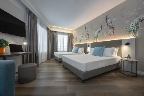 a hotel room with two beds and a tv at IH Hotels Milano Centrale in Milan