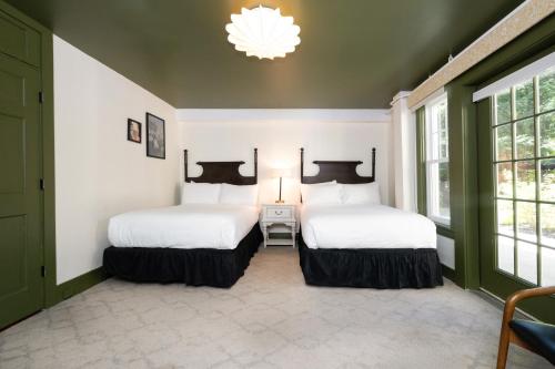 two beds in a room with white walls and windows at The Constance by The Lenox Collection in Lenox
