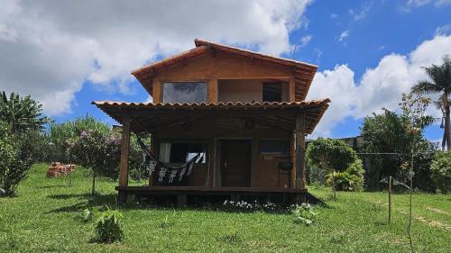 a small house with a roof on a grass field at Chalés Vila Carrancas - Ao lado do centro com piscina, cozinha completa e muita tranquilidade in Carrancas