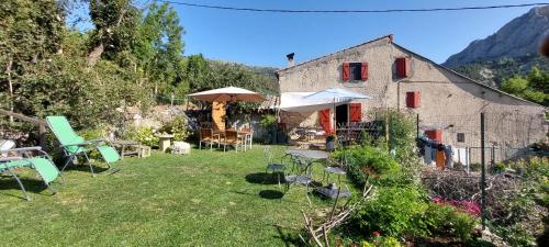 un jardin avec des chaises et des tables ainsi qu'un bâtiment dans l'établissement La Fischaumière, à Soleilhas