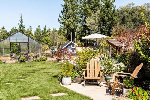 a garden with two chairs and a greenhouse at Kina Ridge Luxury Home w Pool, Sauna and Views in Tasman