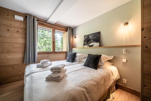 une chambre avec un grand lit avec des serviettes dessus dans l'établissement CHALET PASCAL A101: 3 chambres + cabine neuf pour 8 personnes, à Morzine