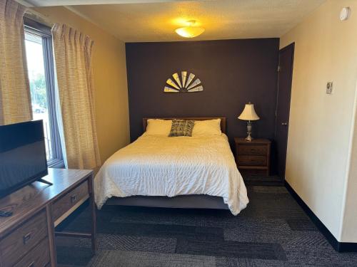 a bedroom with a bed and a dresser and a tv at Rustic Lodge in Glasgow