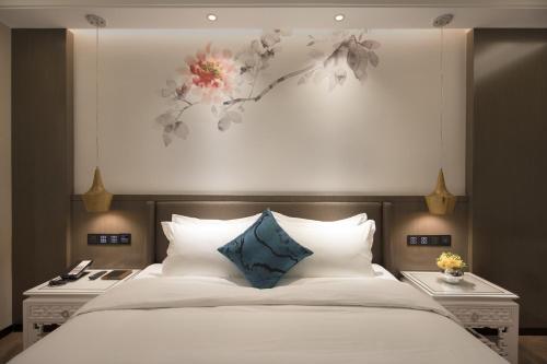 a bedroom with a large bed with white sheets and blue pillows at Paco Hotel Dongpu Guanghzou -Free Shuttle Bus for Canton Fair in Guangzhou