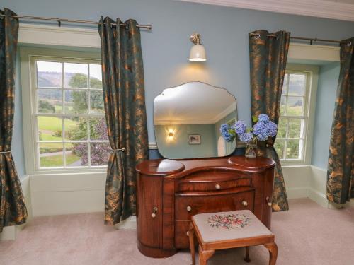 a dressing room with a mirror and a wooden dresser at Llwynderw Hall in Llanwrtyd Wells