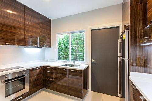 a kitchen with wooden cabinets and a sink and a window at Sukhumvit 16 Townhouses, InHome Luxury Residences in Bangkok