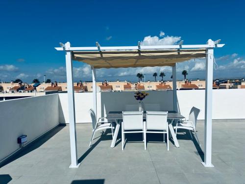 a table and chairs under a canopy on a roof at Alicante City Beach Jacuzzi Luxury Penthouse with Rooftop Terrace in Gran Alacant