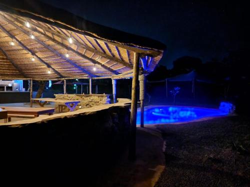 a swimming pool at night with a wooden pergola at La Hacienda in uMhlali