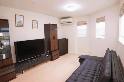 a living room with a couch and a flat screen tv at 全新设备设施 3层102平方独栋洋房4室1厅2卫2个洗澡间 厨房完备 交通便利 in Tokyo
