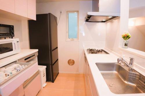 a kitchen with a sink and a black refrigerator at 全新设备设施 3层102平方独栋洋房4室1厅2卫2个洗澡间 厨房完备 交通便利 in Tokyo