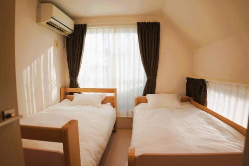 two beds in a small room with a window at 全新设备设施 3层102平方独栋洋房4室1厅2卫2个洗澡间 厨房完备 交通便利 in Tokyo