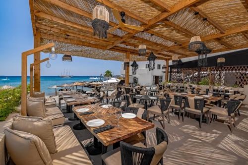 a restaurant with tables and chairs and the ocean at Silver Beach Hotel in Kardamaina