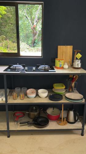 a shelf filled with plates and bowls and pans at Deer House Cabuya in Cabuya