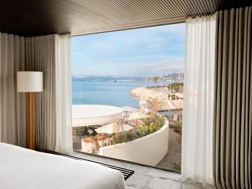 a room with a large window with a view of the ocean at Cap d'Antibes Beach Hotel in Juan-les-Pins