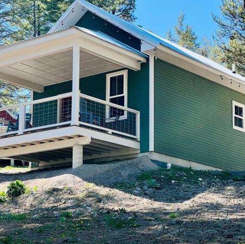 a green house with a large front porch with a balcony at Elk Ridge Village 201A Cozy Cabin with views of Flathead Lake and the mountains in Lakeside