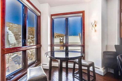 a table and chairs in a room with windows at Village Hall 12 by East West Hospitality in Beaver Creek