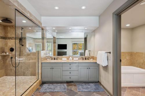 a bathroom with a shower and a tub and a sink at Village Hall 09 by East West Hospitality in Beaver Creek