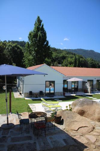 a patio with a table and chairs and an umbrella at Quinta das Pedrosas in Arouca