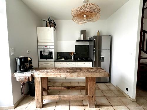 une cuisine avec une table en bois et un réfrigérateur dans l'établissement La Cachette Enchantée, à Néant-sur-Yvel