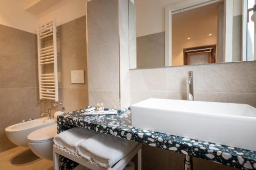 a bathroom with a sink and a toilet and a mirror at Profumi di Primavera Luxury Rooms & Suite in Matera