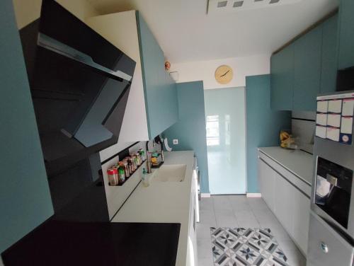 Il comprend une cuisine dotée de murs bleus et d'un réfrigérateur blanc. dans l'établissement Big, Newly Renovated and Bright 3 Bedroom Flat in center of Courbevoie - 89m2, à Courbevoie