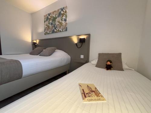 - une chambre d'hôtel avec 2 lits et un livre dans l'établissement Hôtel Le Valois, Cognac Centre, à Cognac