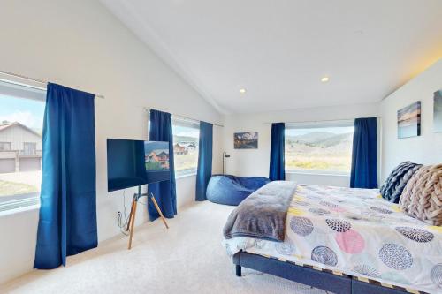 a bedroom with blue curtains and a bed with a tv at Sakura House in Tabernash