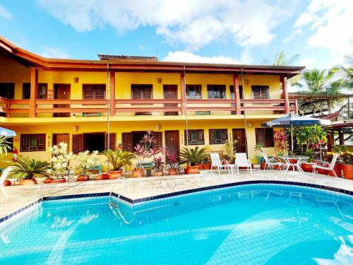 a hotel with a swimming pool in front of a building at Residencial Villa Cris - Jd. São Lourenço/Itaguaré in Bertioga