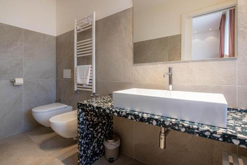 a bathroom with a sink and a toilet and a mirror at Profumi di Primavera Luxury Rooms & Suite in Matera
