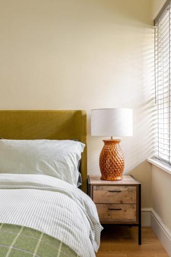 a bedroom with a bed and a lamp on a nightstand at Spacious Country Cottage Sleeps 7 Near Bath Fire Pit Dog Friendly in Bradford on Avon