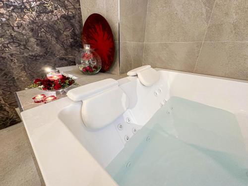 a white bath tub with a red flower on a counter at Profumi di Primavera Luxury Rooms & Suite in Matera