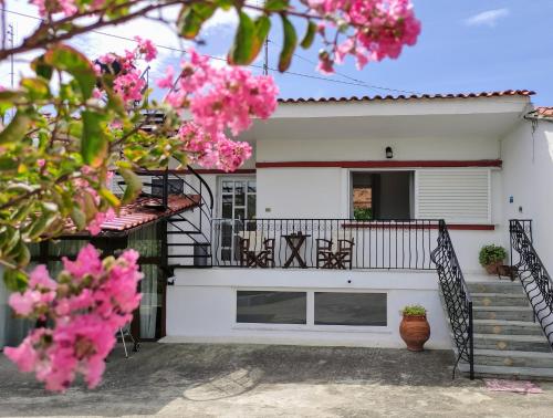 a white house with pink flowers in front of it at Katerina's Countryside and Sea House in Nea Iraklia