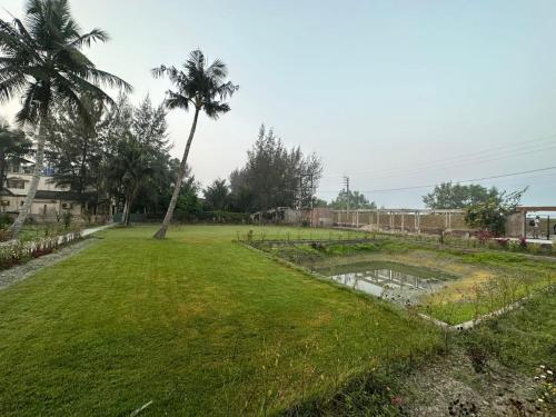 a park with a palm tree and a pond at Sunderban Tiger Residency in Gosāba