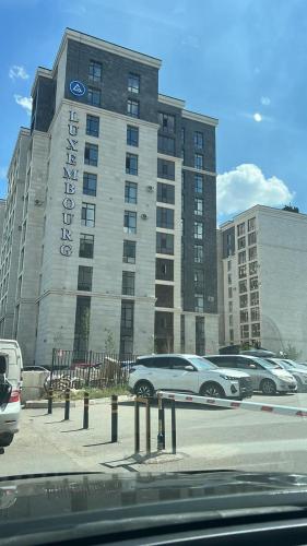 duży budynek z samochodami zaparkowanymi na parkingu w obiekcie Luxembourg w mieście Taldykolʼ