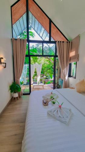 a bedroom with a large bed and a large window at Chertarn Homestay in Ban Pang Bo Hu Bon
